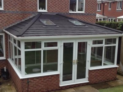 Solid tiled conservatory roof with skylights on a white uPVC conservatory with brick base, installed at a Chelmsford home.