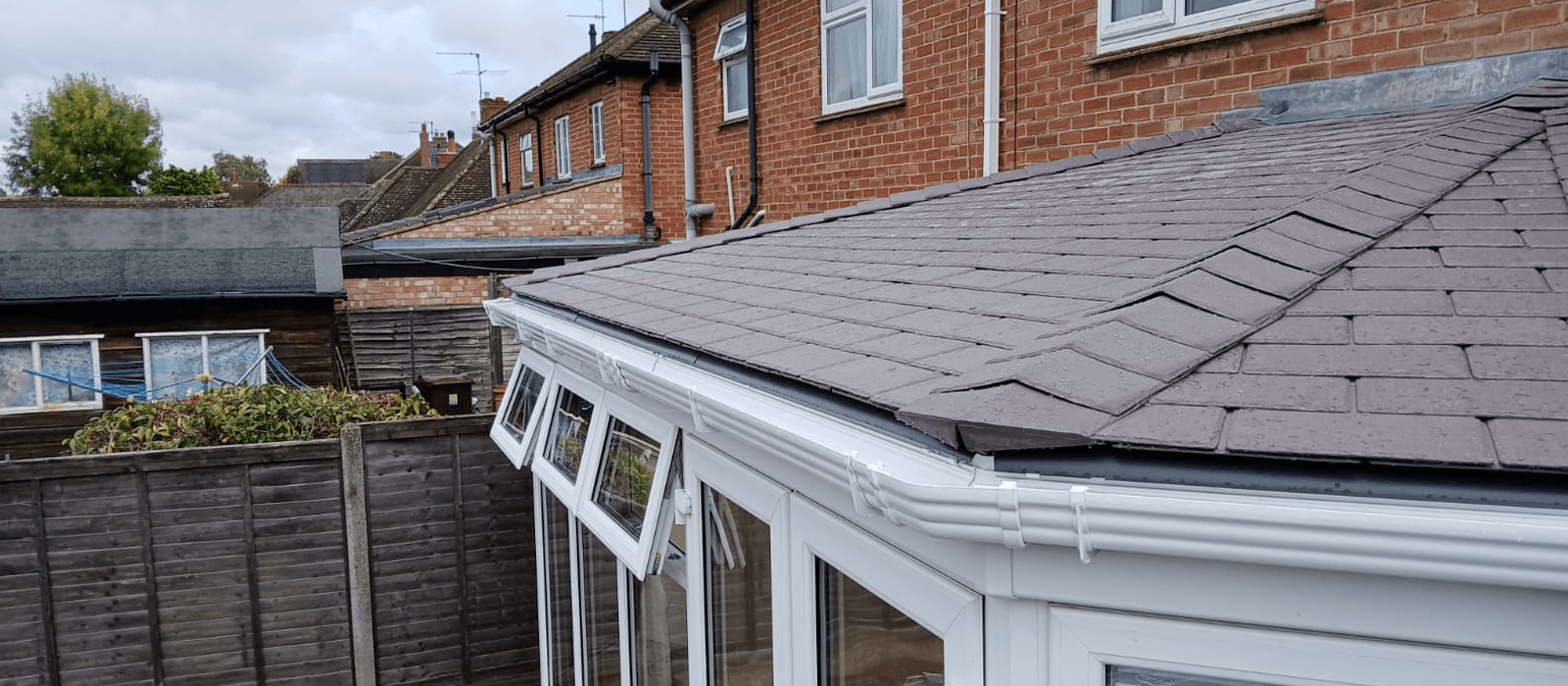 Grey tiled conservatory roof installed on a white-framed conservatory, providing improved insulation and weather protection.