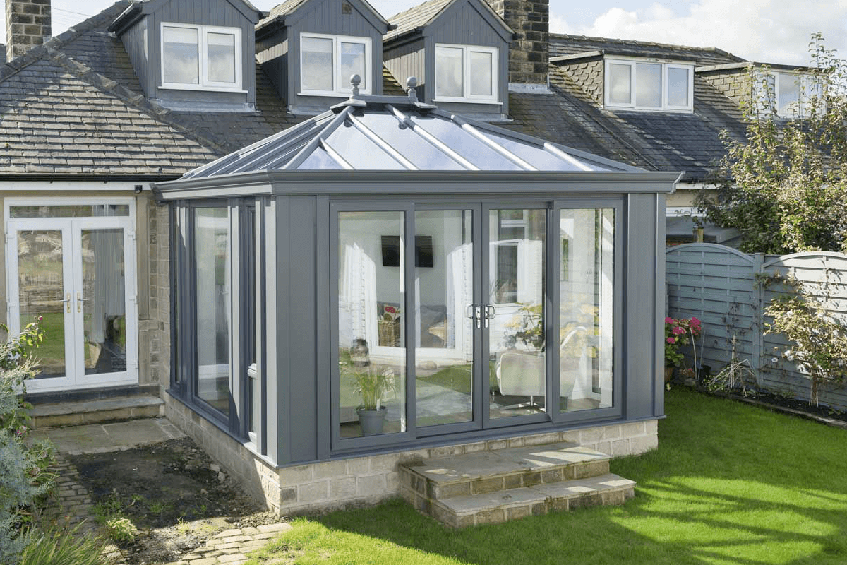 A modern grey glass-roof conservatory in {location}, attached to a traditional home, providing a bright and insulated living space.