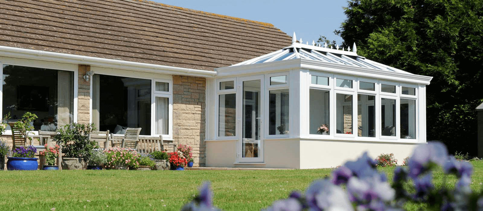 A modern white conservatory in {location}, featuring a glass roof and large windows, extending a home’s living space into the garden.