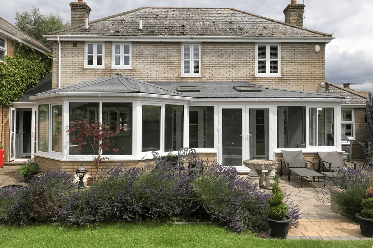 P-shaped tiled conservatory roof installed on a large home, improving insulation and enhancing energy efficiency.