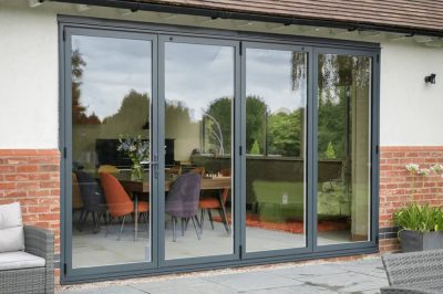 Sheerline grey aluminium bifold doors providing a modern connection between an indoor dining area and an outdoor patio.